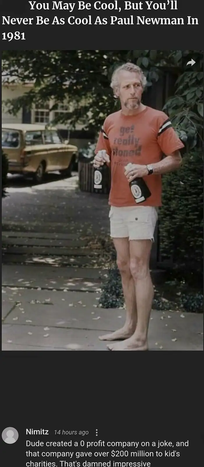 A man with gray hair and a goatee stands barefoot on a sidewalk, wearing an orange t-shirt with 'get really stoned' text and…