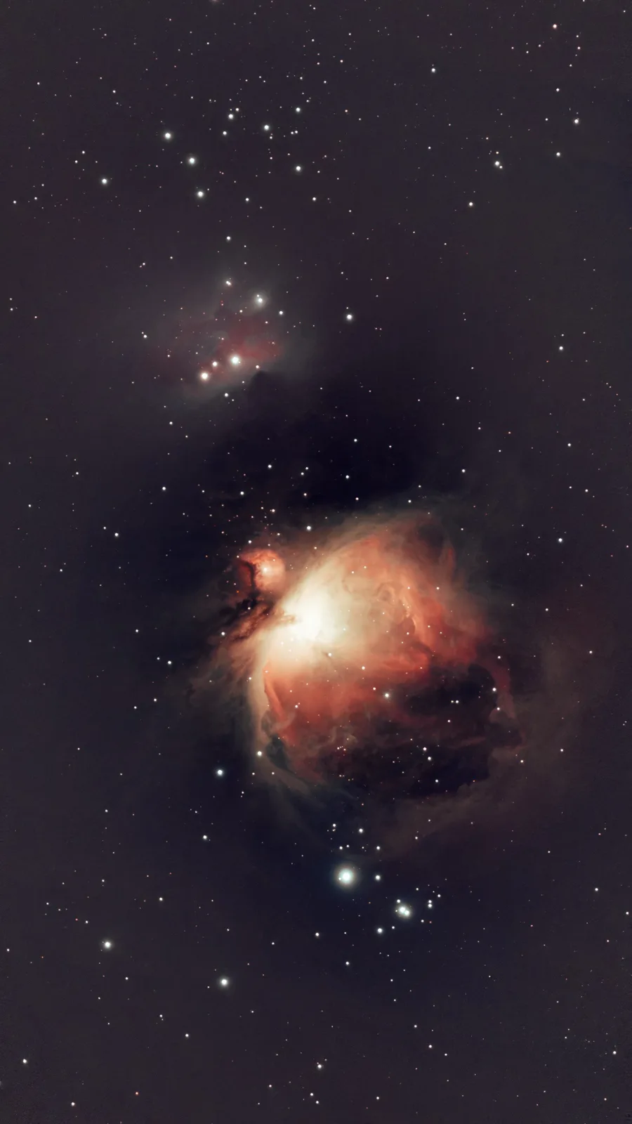 A stunning astrophotograph of the Orion Nebula, featuring glowing red and orange gas clouds, dark dust lanes, and numerous…