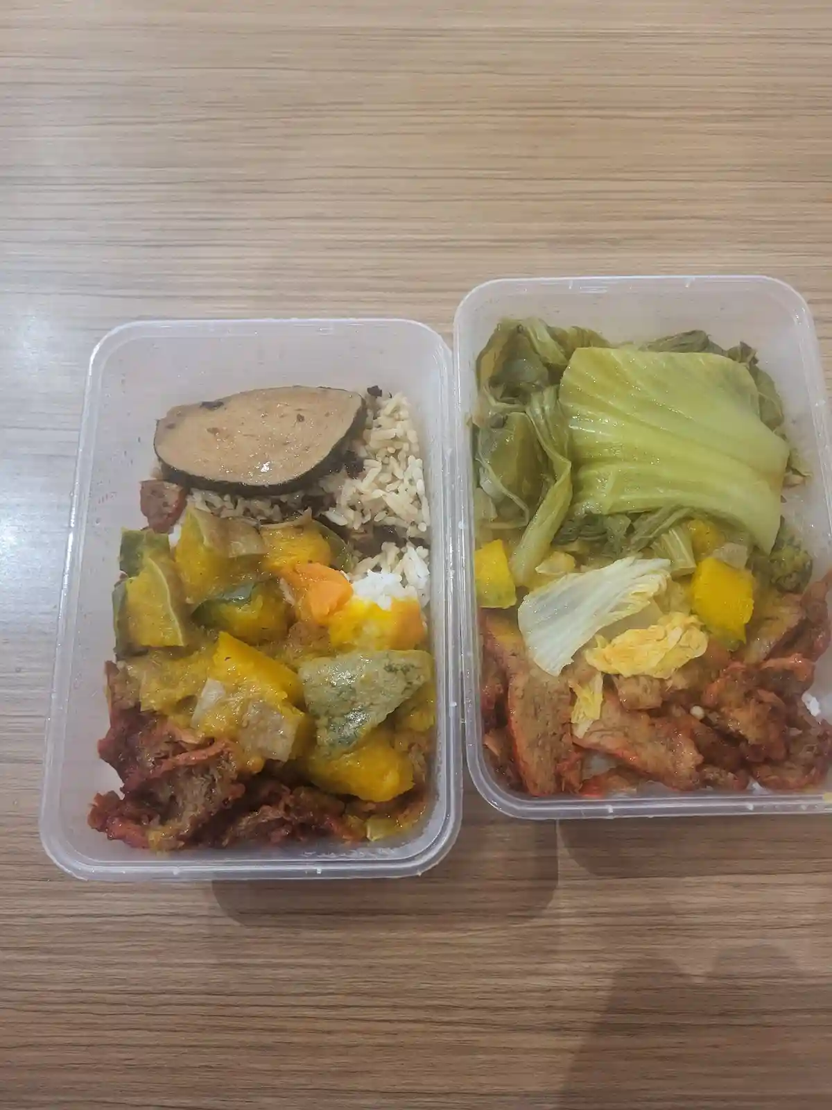 Two clear plastic containers sit side-by-side on a wooden table, each holding a different meal. The left container has rice…