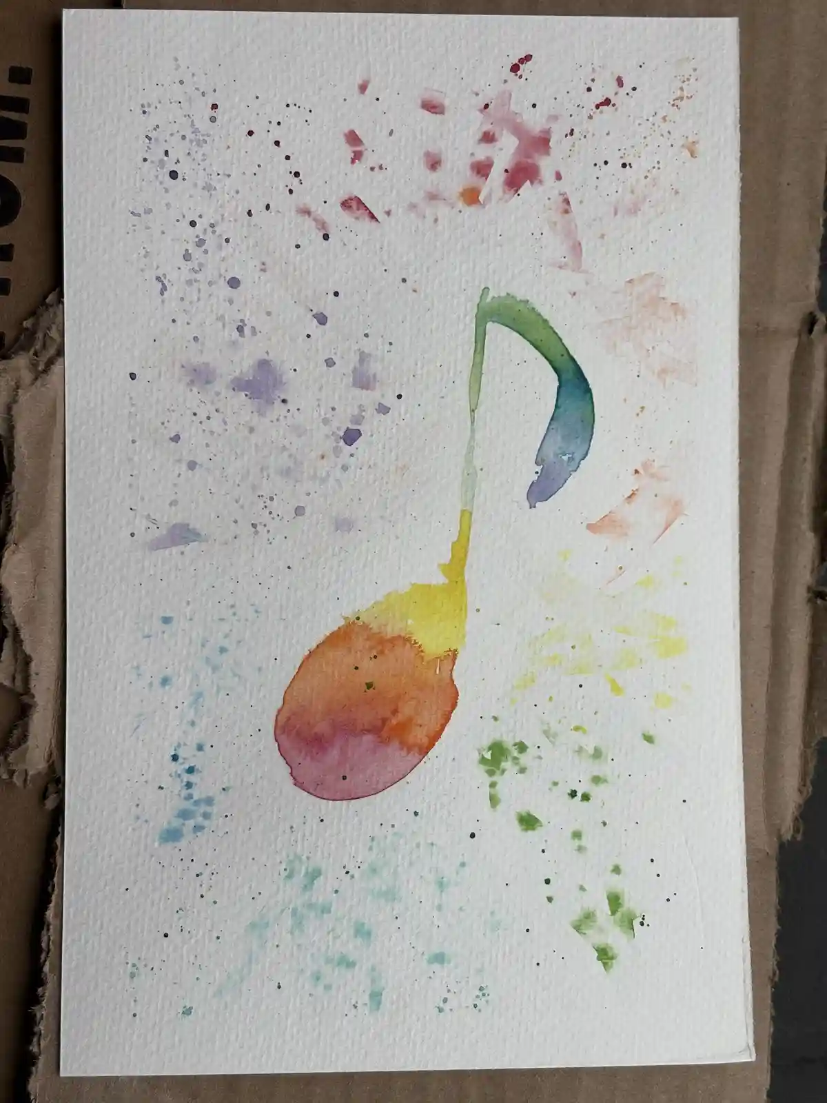 A watercolor painting on textured white paper shows a colorful, abstract musical note with a gradient from orange to yellow…