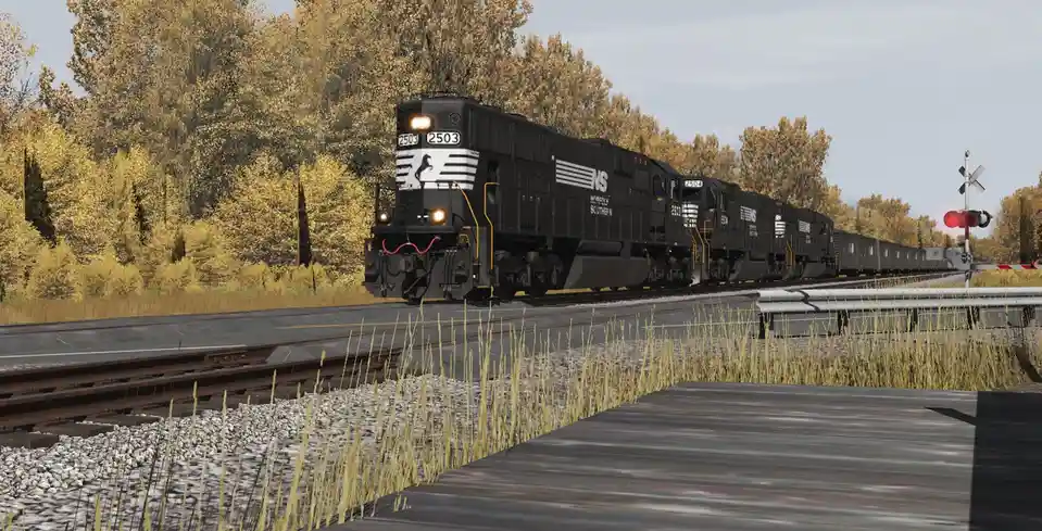 A black Norfolk Southern freight train with locomotives numbered 2503 and 2504 is shown approaching on tracks surrounded by…