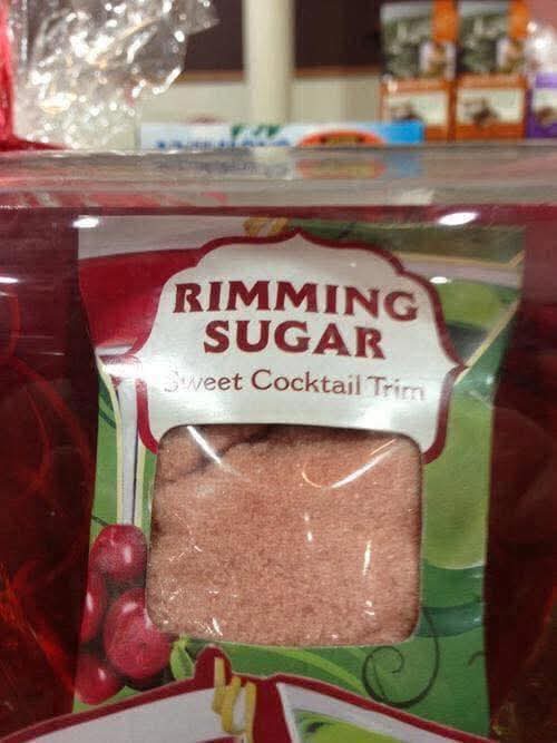 A close-up of a package of 'Rimming Sugar' labeled 'Sweet Cocktail Trim' with a clear window showing pinkish granulated…