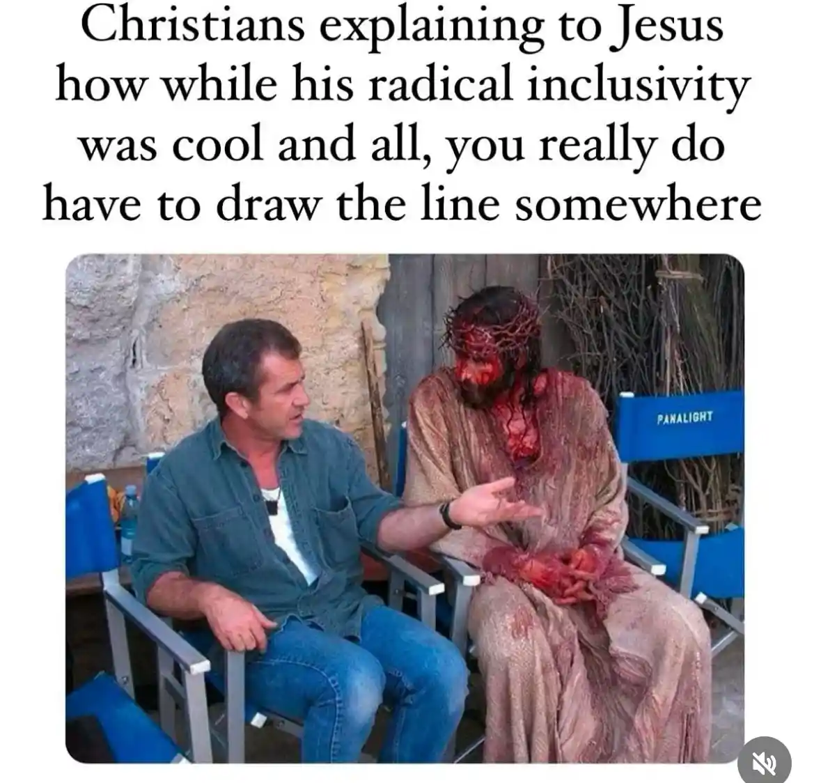A man in casual clothes sits in a blue director's chair talking to an actor dressed as a bloodied, crown-of-thorns Jesus…