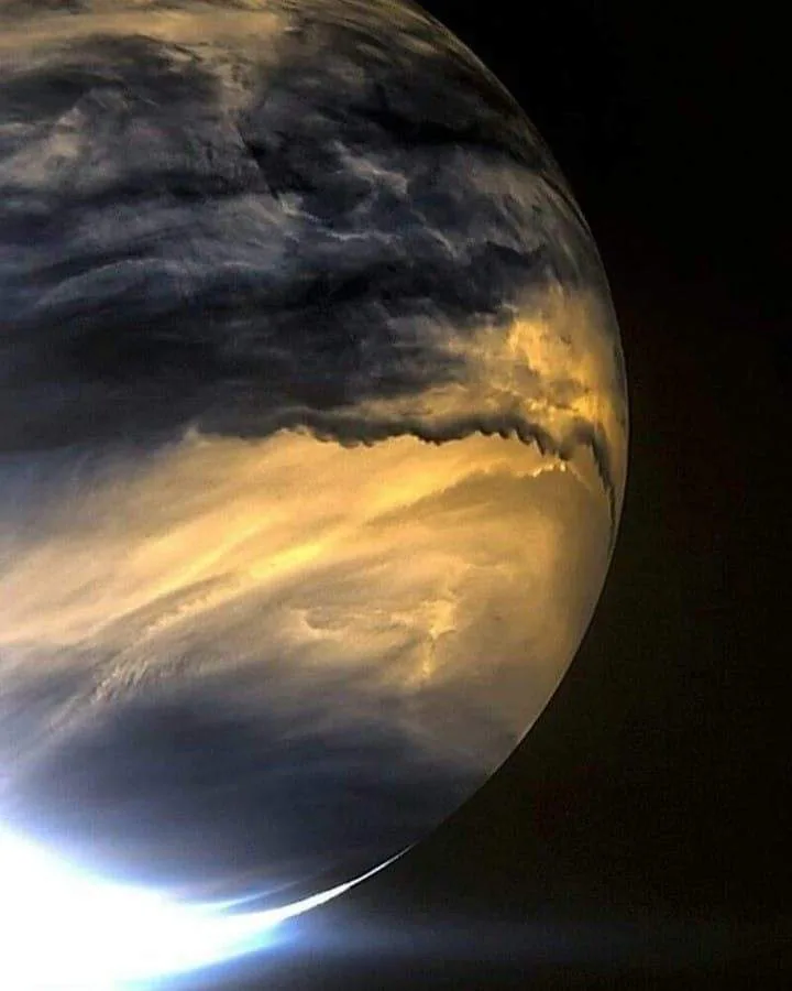 A close-up view of Venus showing its thick, swirling clouds with a bright, glowing horizon where sunlight illuminates the…