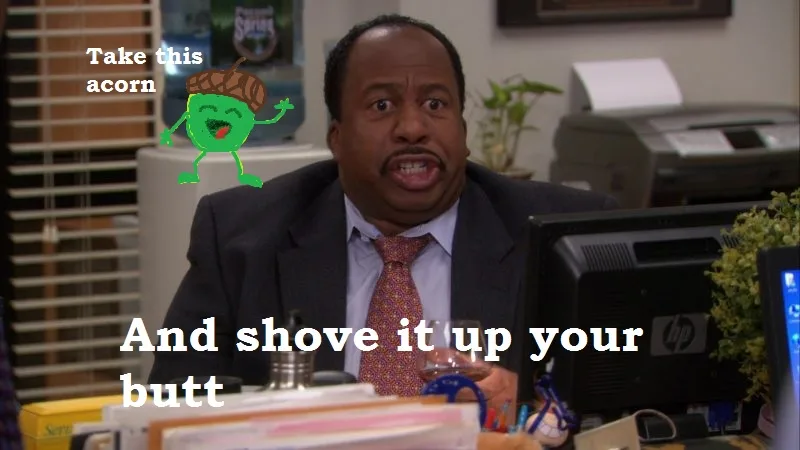 A man in a suit and tie sits at a cluttered office desk with a shocked, angry expression. To his left, a green cartoon acorn…