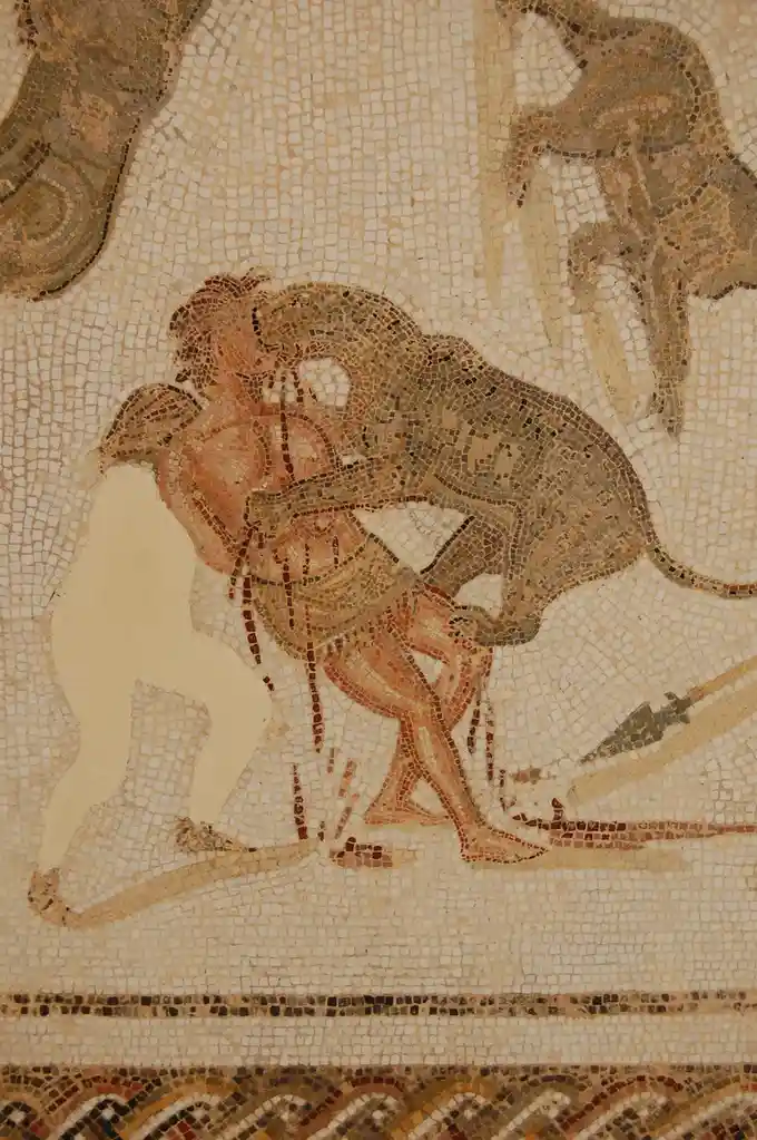 An ancient mosaic depicts a human figure being embraced by a monkey, with a third human figure standing nearby. The overlaid…
