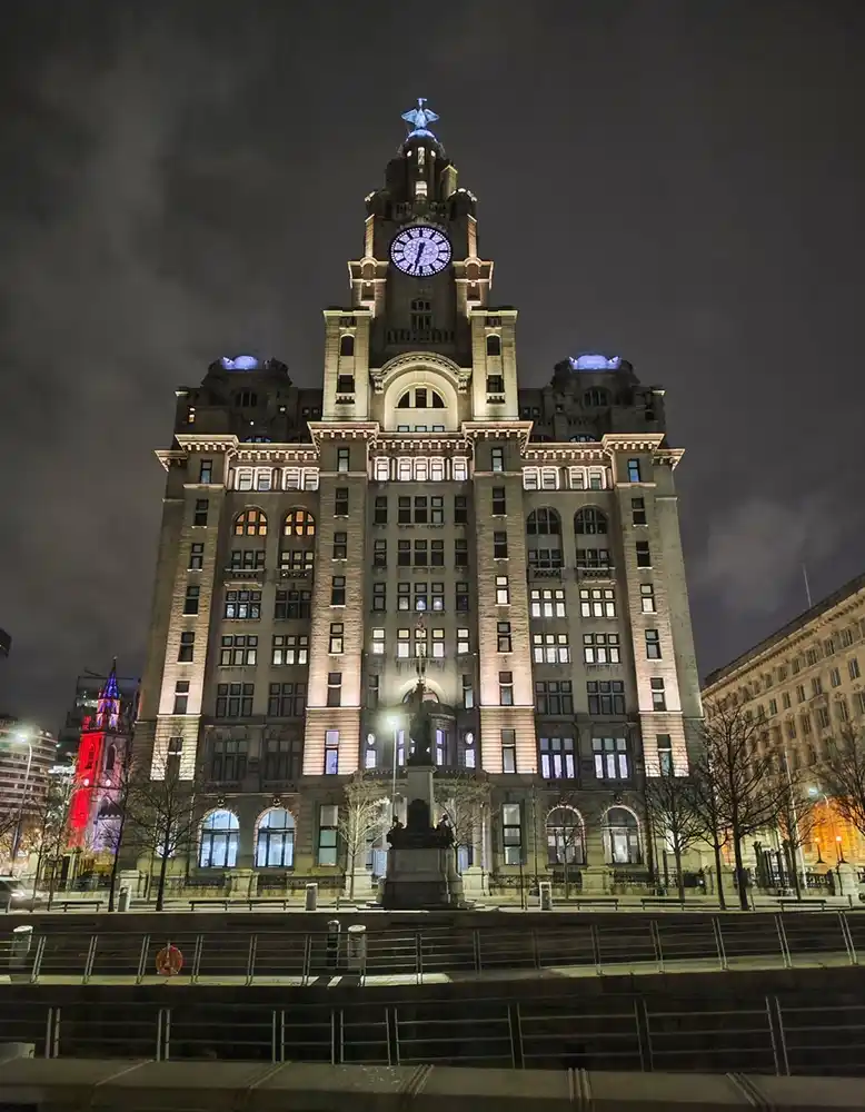 a nighttime photograph of the iconic liver building in liverpool, uk, illuminated against a dark sky. the building's large…