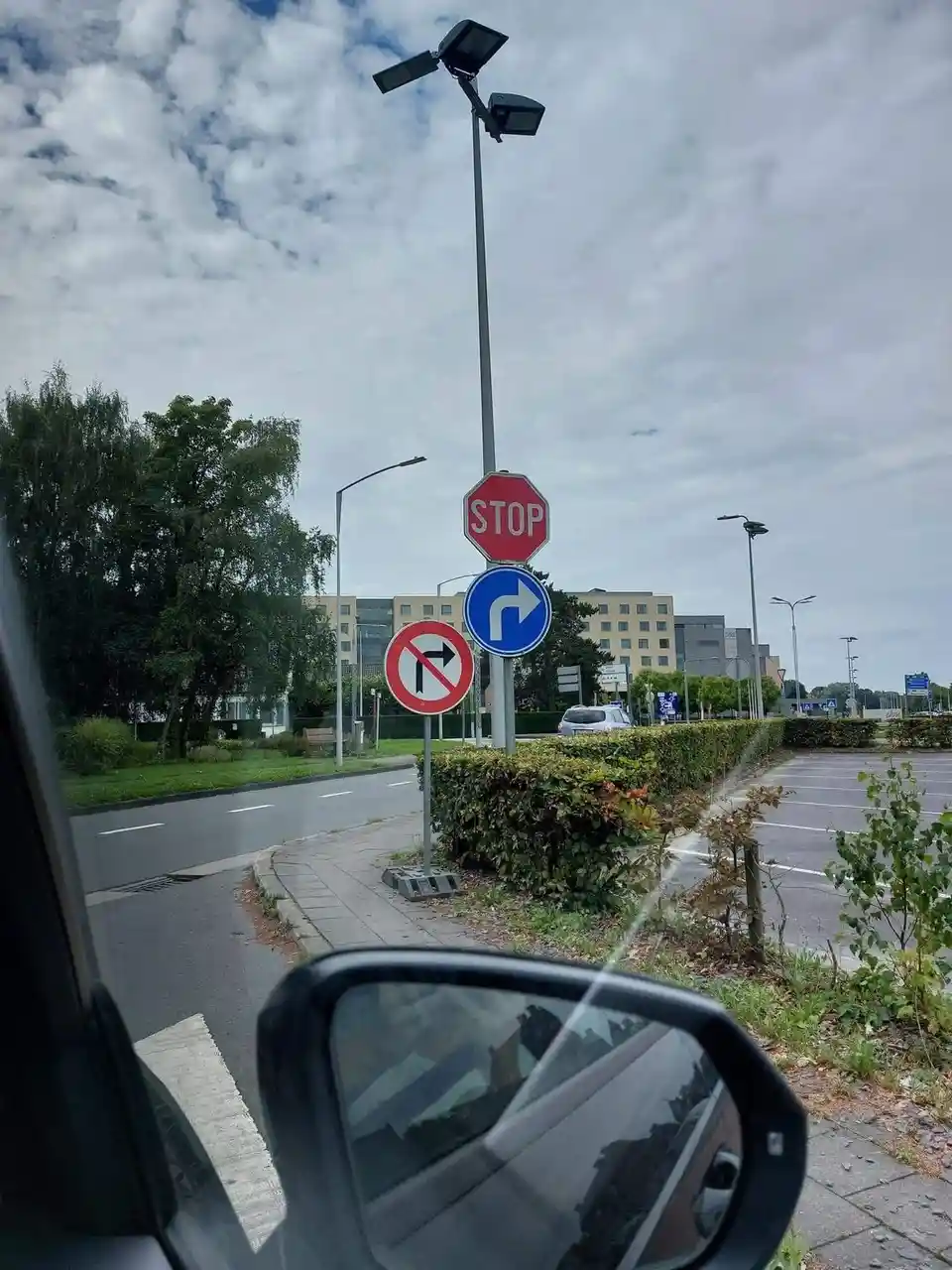 A photo taken from inside a car shows a traffic signpost with a red octagonal 'STOP' sign at the top, a blue circular sign…