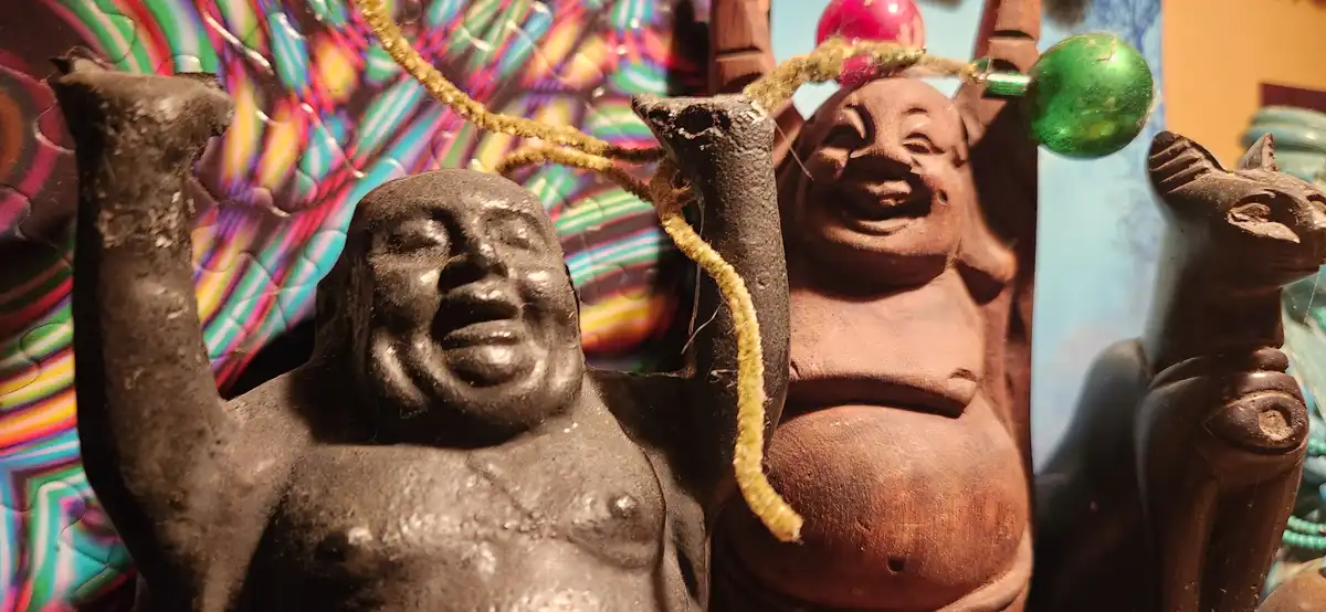 A close-up photo shows three small, dark-colored figurines: one on the left with a grimacing, open-mouthed expression, one…