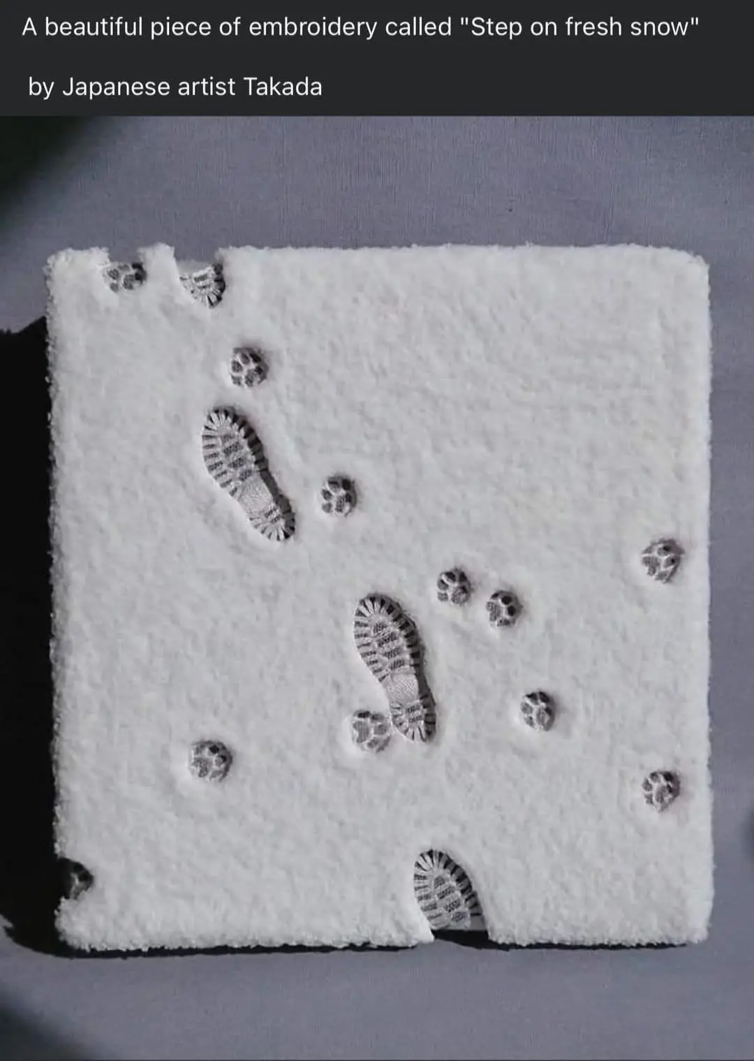 A square piece of white, fluffy fabric resembling snow, with detailed embroidered footprints and paw prints in dark thread…