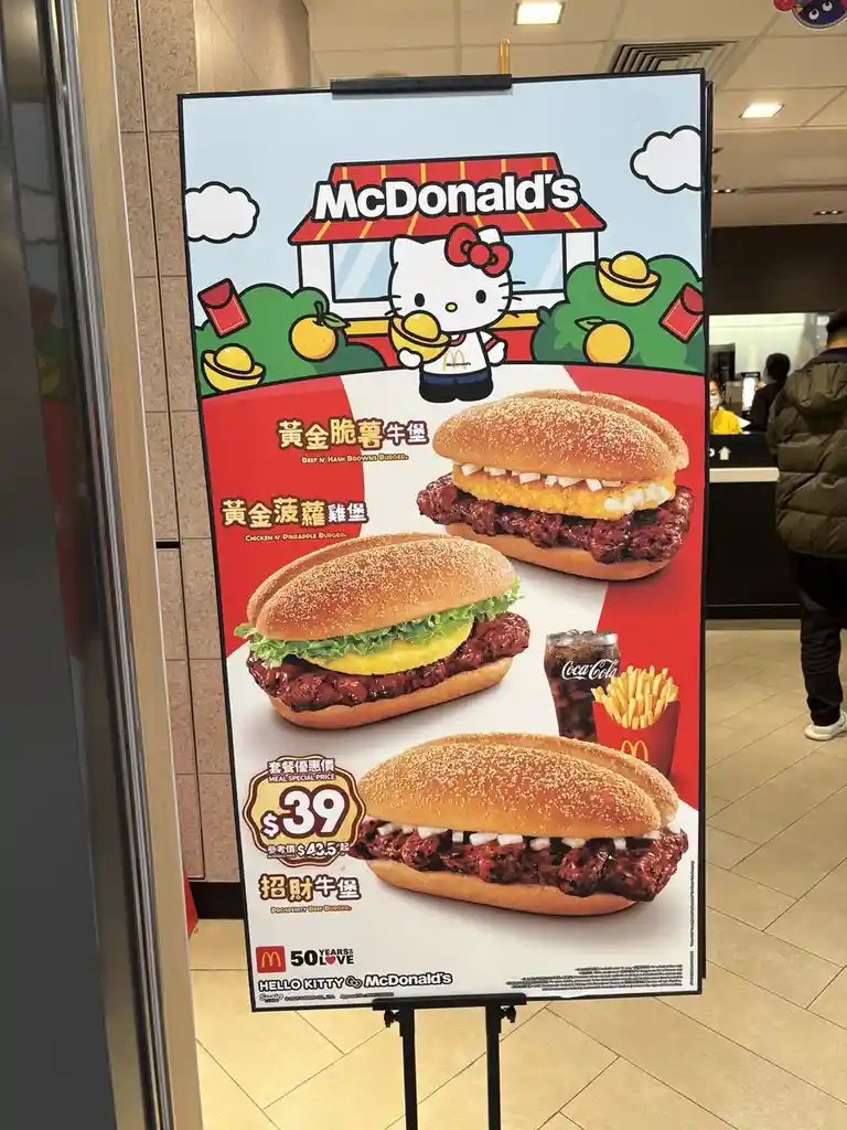 A McDonald's promotional poster features Hello Kitty in a McDonald's uniform holding a gold ingot, advertising three…