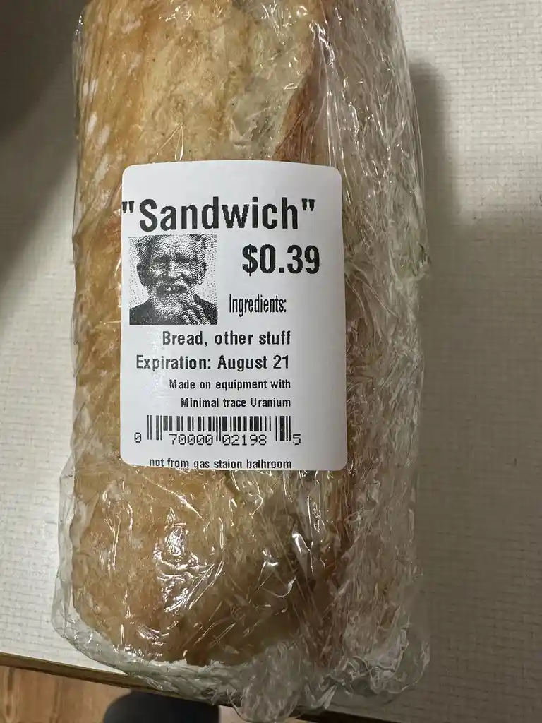 A loaf of bread wrapped in plastic has a mock food label that reads "Sandwich" for $0.39, lists "Bread, other stuff" as…