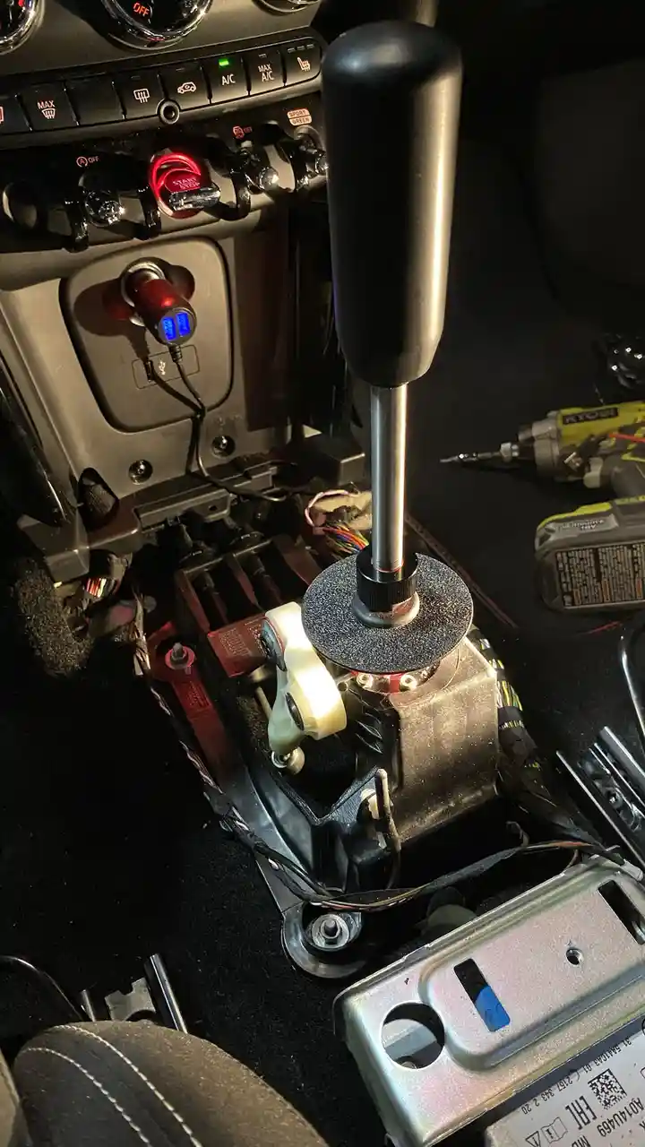 A close-up photo of a car's interior showing a manual transmission gear stick installed in place of an automatic…