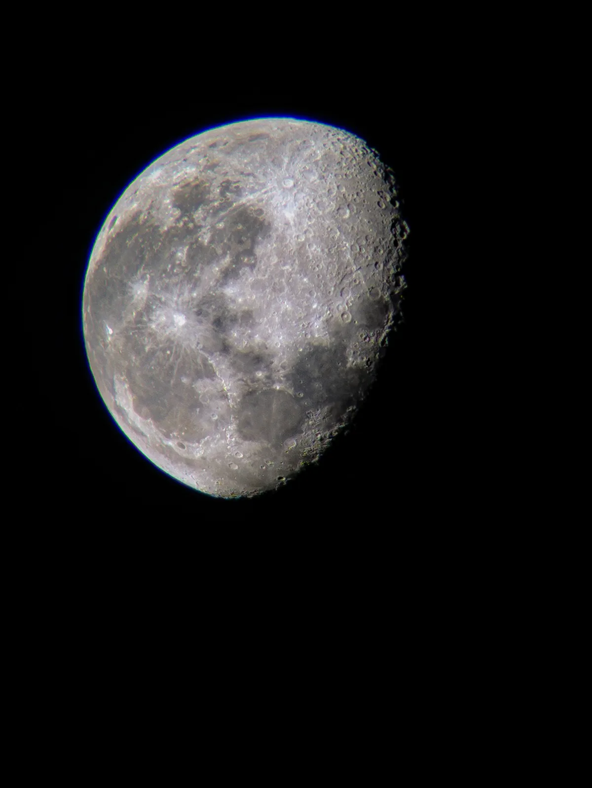 A close-up photograph of the moon against a black sky, showing its cratered surface and illuminated edge. The image has no…