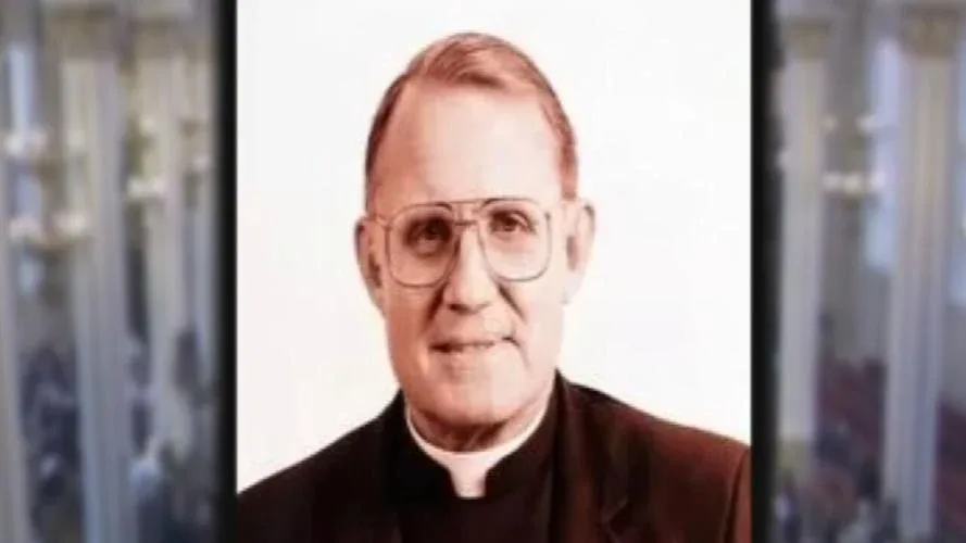 A portrait of an older man with glasses and a clerical collar, wearing a dark suit, with the overlaid text 'i'm not a…