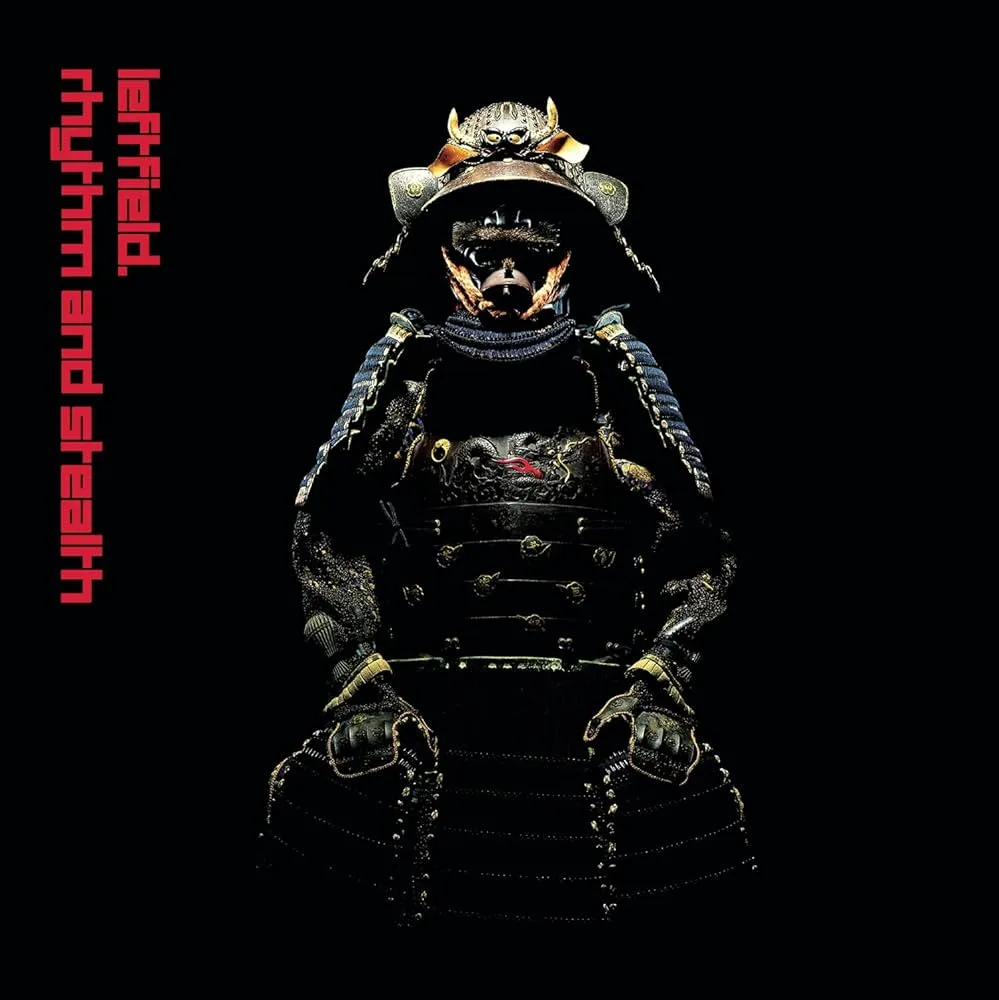 A person in full black samurai armor with a menacing mask and horned helmet stands against a black background. Red text on…