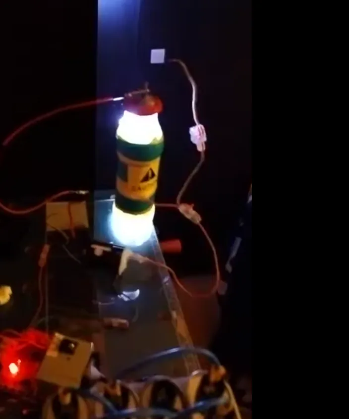 A homemade contraption features a repurposed fire extinguisher bottle glowing brightly from within, connected by wires to an…