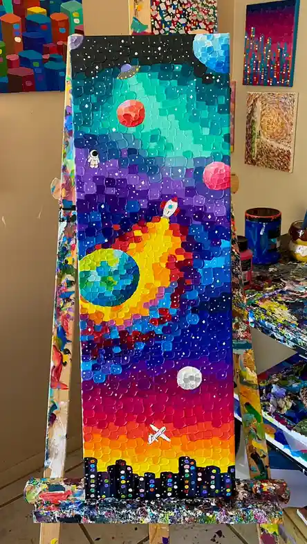 A vibrant, textured painting on an easel depicts a surreal scene with a city skyline at the bottom, a rocket ship, planets…