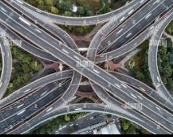 An aerial view of a complex, multi-level highway interchange with numerous curved roads and lanes converging and diverging…