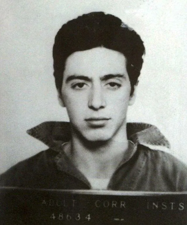 A black and white mugshot of a young man with dark hair and a collared shirt, looking directly at the camera. The text…