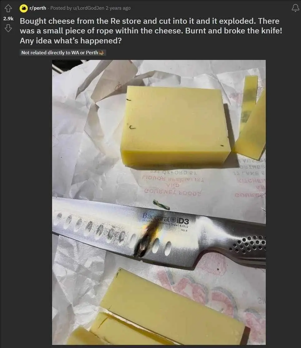 A block of yellow cheese sits on crumpled paper next to a knife with a melted, burnt spot on its blade. The knife, branded…