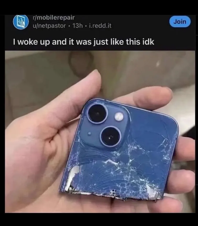 A hand holds a severely damaged blue smartphone with a shattered back panel and broken camera module. The overlaid text…
