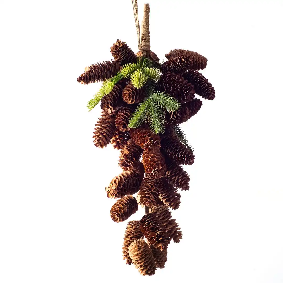 A decorative hanging arrangement composed of numerous brown pinecones and sprigs of green pine needles, tied together with…