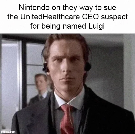 A man in a suit and red tie with a headset stares intensely at the camera, with another person blurred in the background…