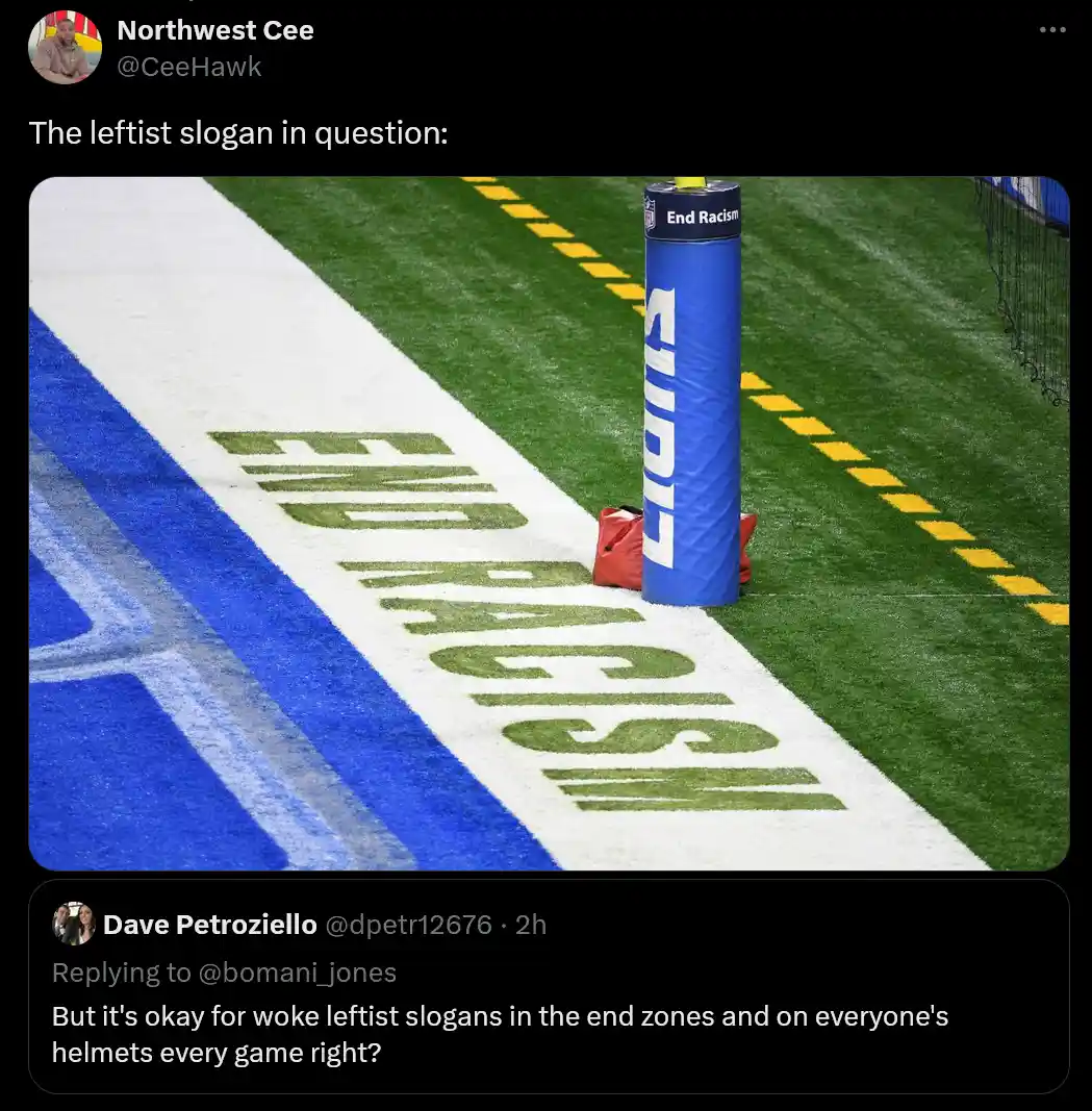 A close-up photo of an American football field end zone shows the words 'END RACISM' painted in green on the white turf. A…