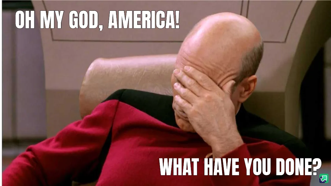 A bald man in a red Starfleet uniform sits in a chair, covering his face with his hand in a gesture of despair or disbelief…