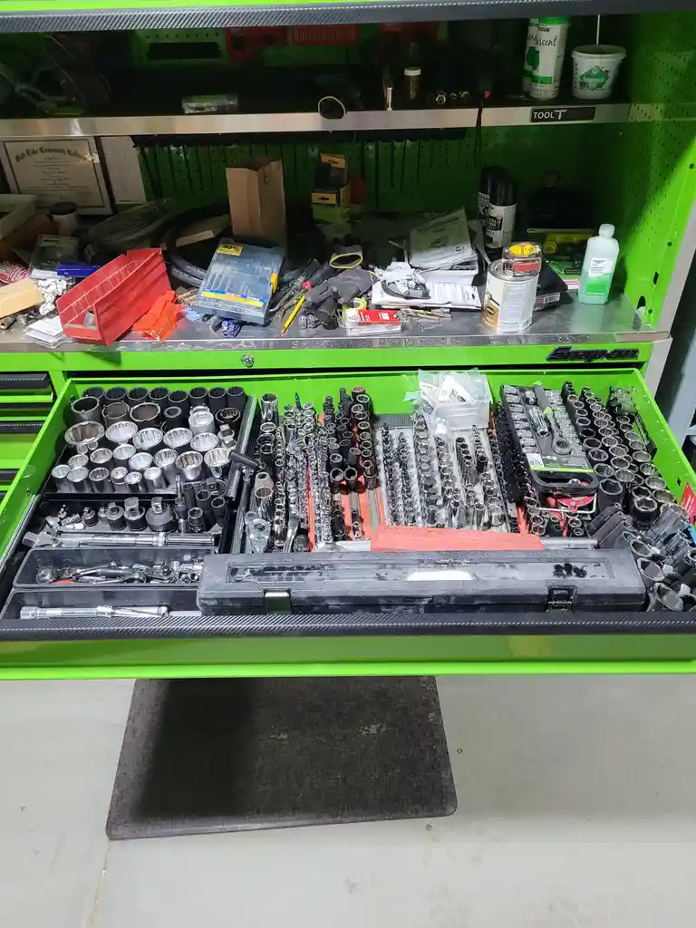 A bright green Snap-on tool chest with its largest drawer pulled out, revealing an extensive, meticulously organized…