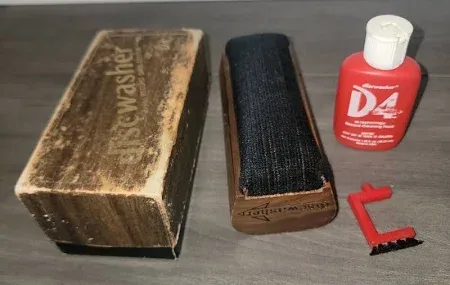 A collection of vintage cleaning tools including a worn wooden box labeled 'Frewasher', a wooden brush with black bristles…