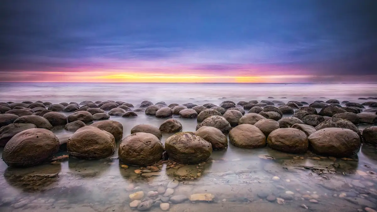 Against a vibrant sunset, Bowling Ball Beach near Point Arena showcases striking spheroid boulders, known as concretions…