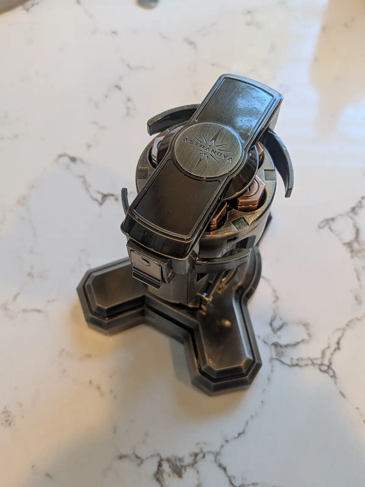 A close-up photo shows a dark metallic, futuristic-looking device with a circular base and a central component labeled…