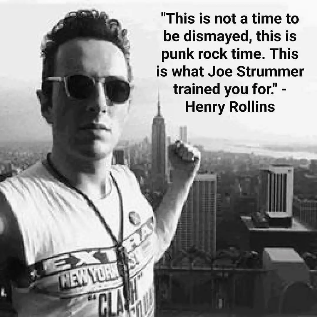 A black-and-white photo of a man wearing sunglasses and a tank top with "EXTRA NEW YORK" text, standing on a rooftop…