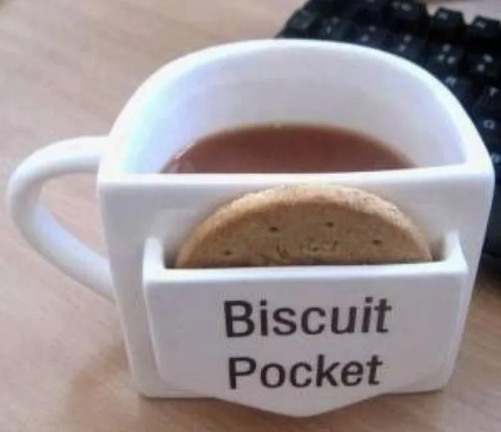 A white ceramic mug with a built-in compartment labeled 'Biscuit Pocket' holds a round biscuit while the main section…