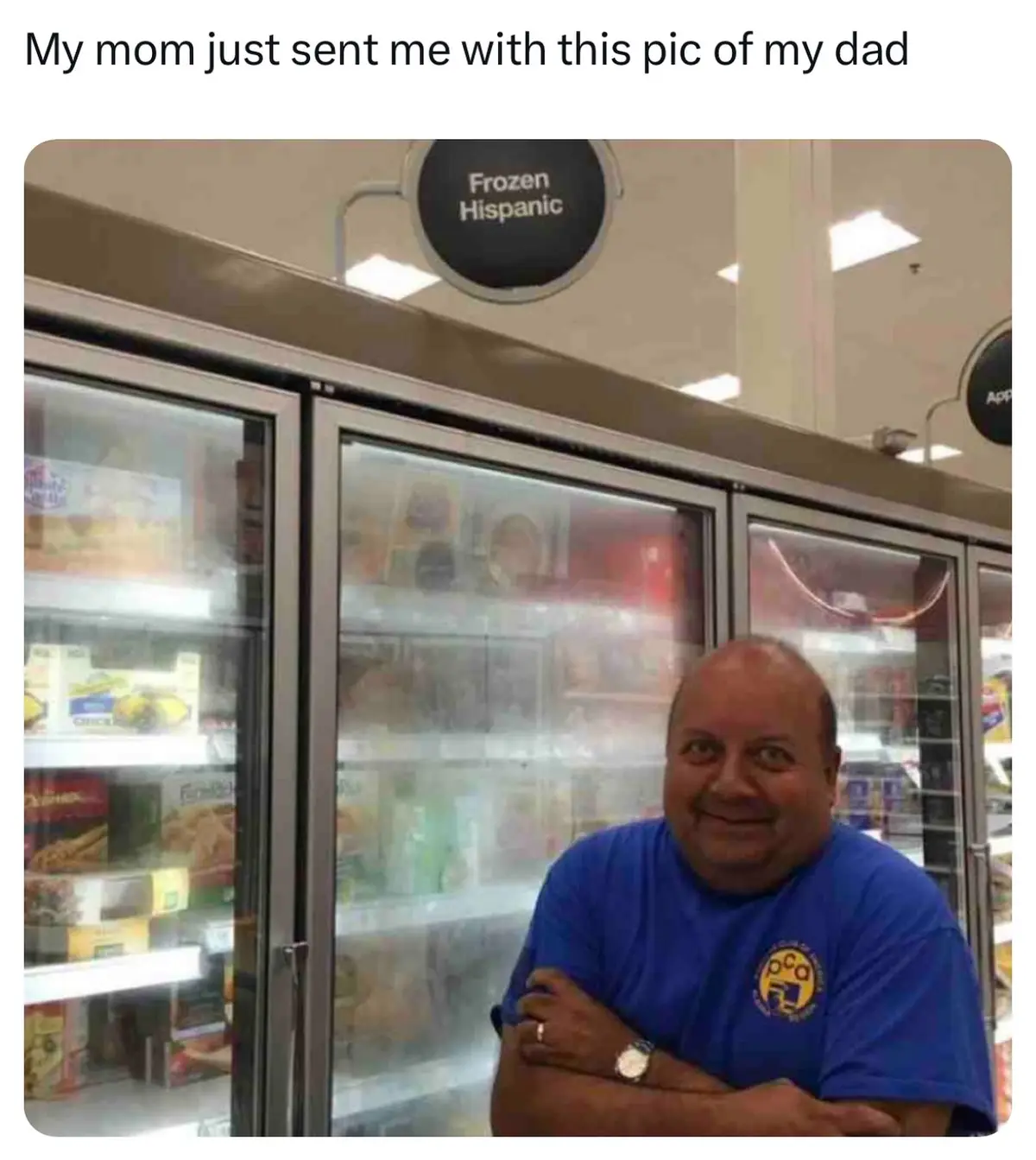 A man in a blue shirt stands in front of a supermarket freezer aisle, arms crossed, smiling. Above him, a circular sign…