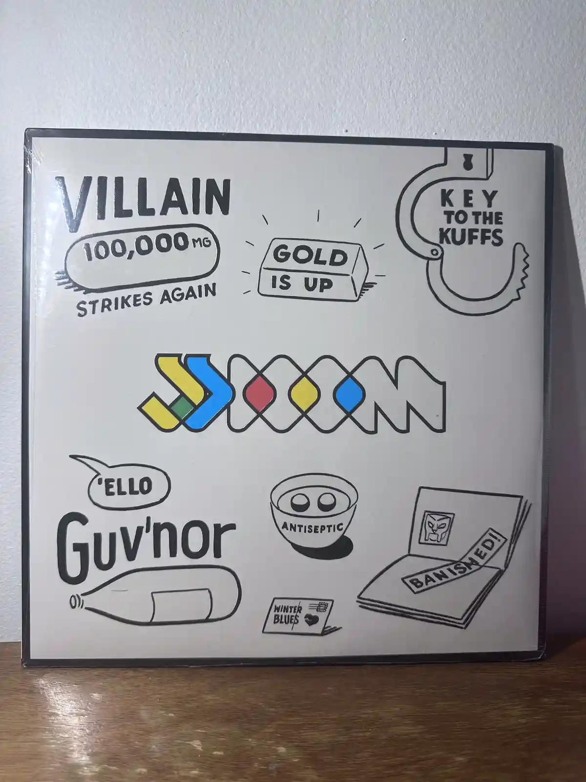A white poster with black line drawings and colorful accents shows various items with text: 'VILLAIN 100,000MG STRIKES…