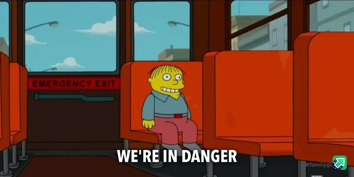 A cartoon boy with yellow skin and a wide, nervous grin sits alone on a red bus seat. Behind him, an emergency exit door is…