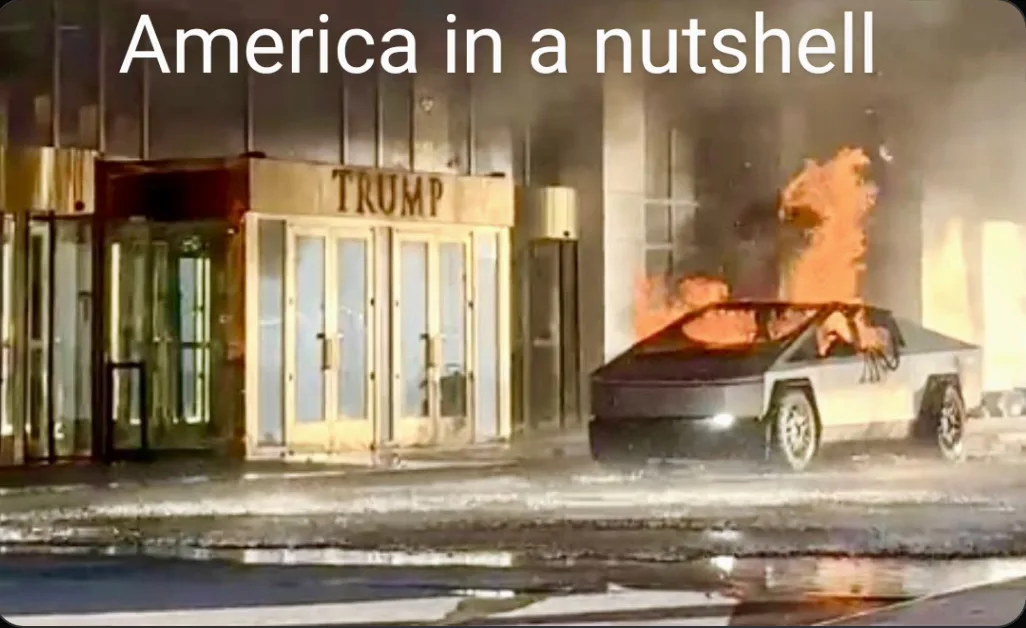 A burning Tesla Cybertruck is parked outside a building with a prominent 'TRUMP' sign above its entrance, with smoke and…