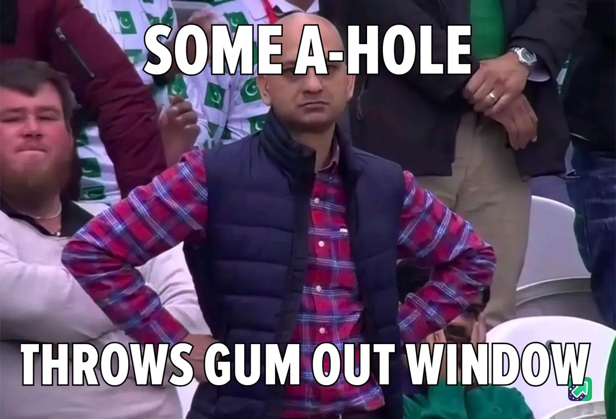 A bald man in a red plaid shirt and black vest stands with hands on hips in a stadium, looking annoyed. The text overlaid on…