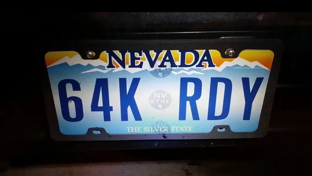 A Nevada license plate with the text '64K RDY' is shown, featuring a mountain and sunset design with 'THE SILVER STATE' at…