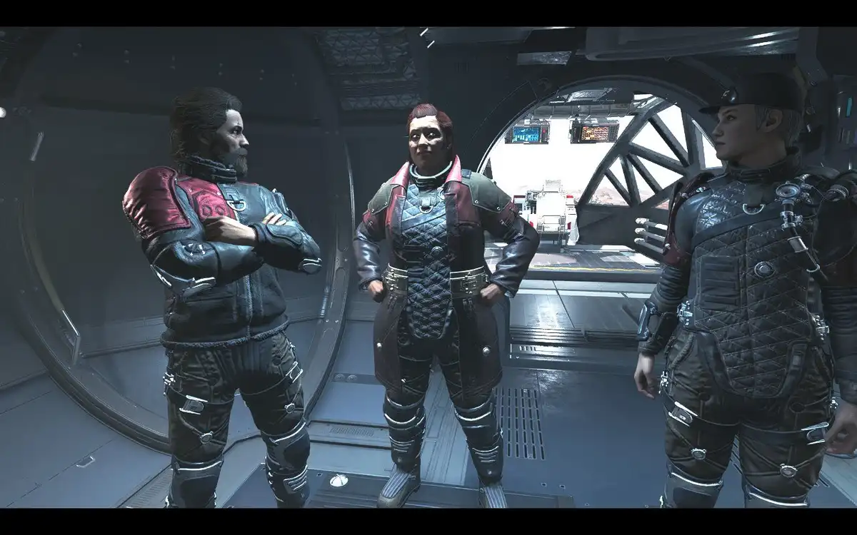 Three characters in sci-fi armor stand inside a spaceship corridor. The central figure, with red hair and a confident smirk…