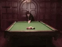 A man in a tuxedo stands behind a pool table, initially preparing to take a shot. After striking the cue ball, the balls…