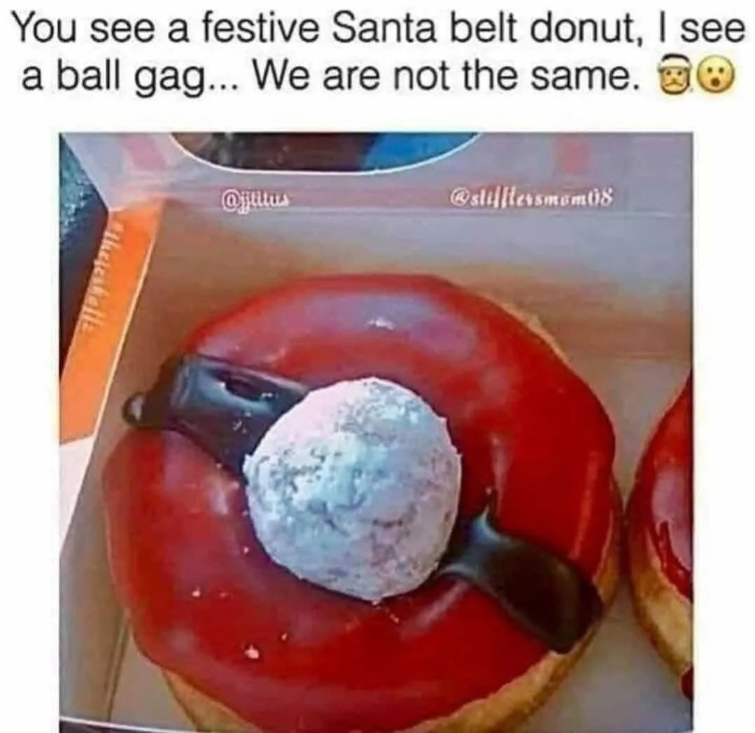 A close-up photo of a donut with red icing, a powdered sugar ball in the center, and a black chocolate drizzle forming a…