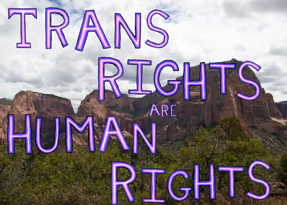 A scenic photo of red rock canyon formations under a cloudy sky, overlaid with large, glowing purple neon-style text that…