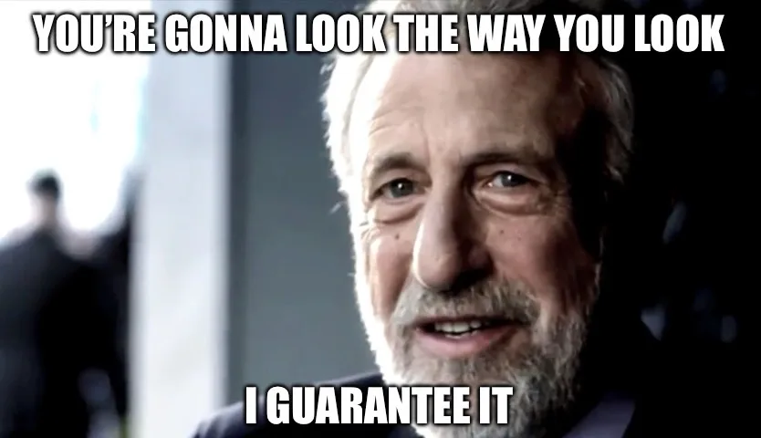 A close-up of an older man with gray hair and a beard, wearing a suit, looking directly at the camera with a knowing…