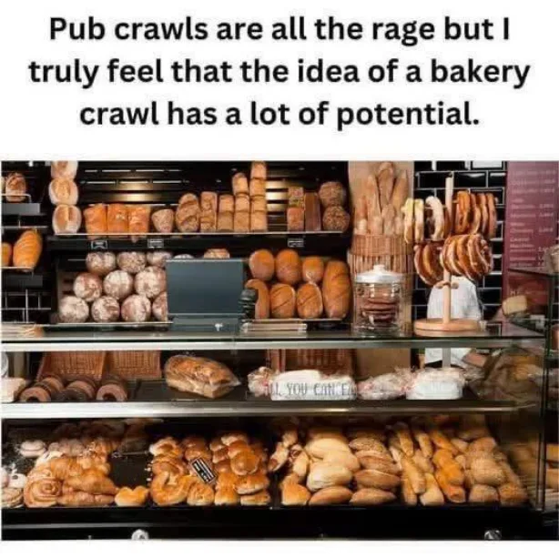 A bakery display case filled with various types of bread and pastries on multiple shelves, with a laptop sitting on one of…