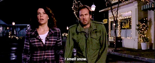 A still image from the movie 'The Holiday' shows a man and a woman standing side by side on a decorated street at night. The…