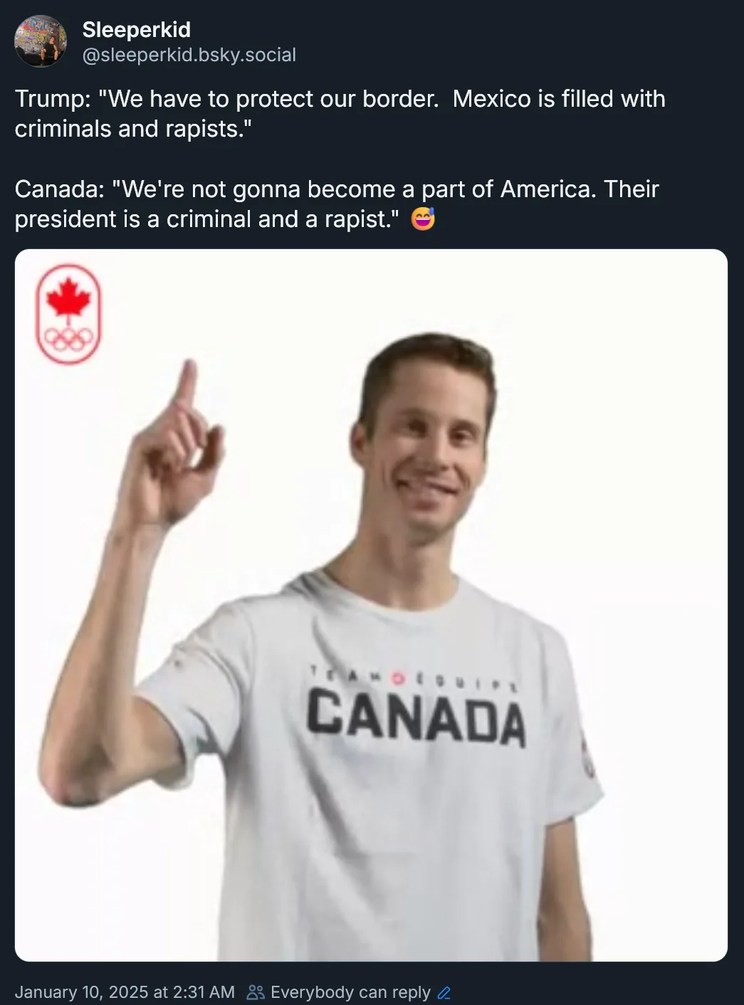 A man in a white 'Team Canada' t-shirt points upward with his right index finger while smiling. In the top left corner, a…